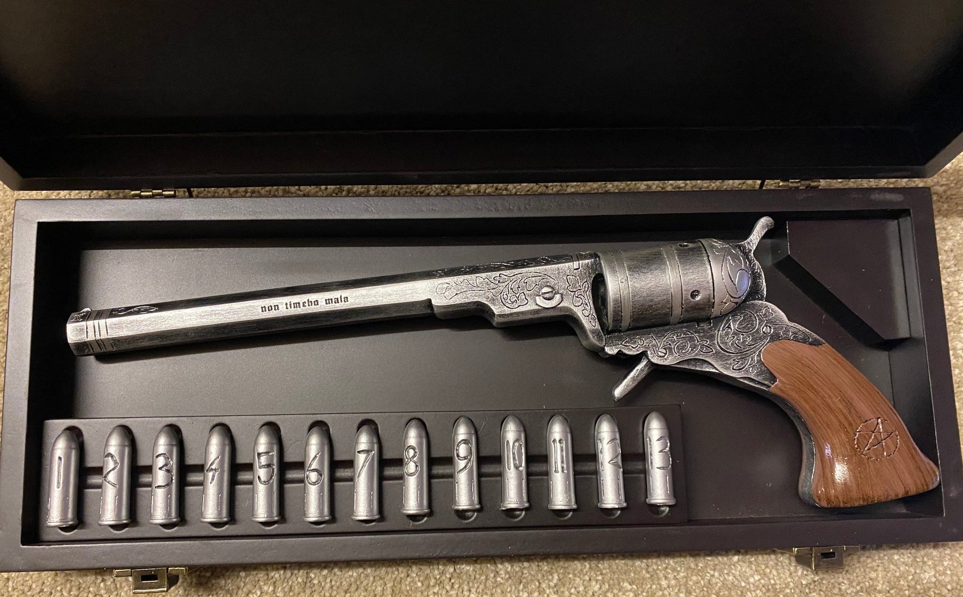 Decorative revolver with wooden grip and metal components in a display case.