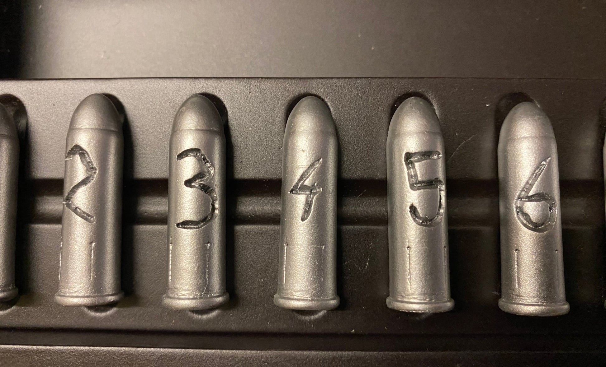 Set of six metallic bullets with engraved numbers on a dark background