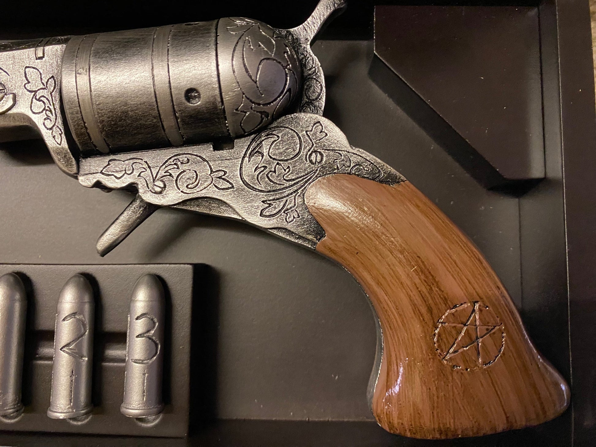 Decorative revolver with wooden grip and metal accents, accompanied by bullets on a dark background.