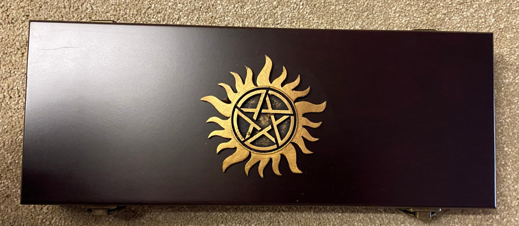 Black box with gold symbol on a beige carpet