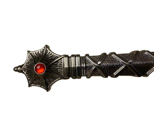 Decorative object with star design and red gemstone on a textured surface