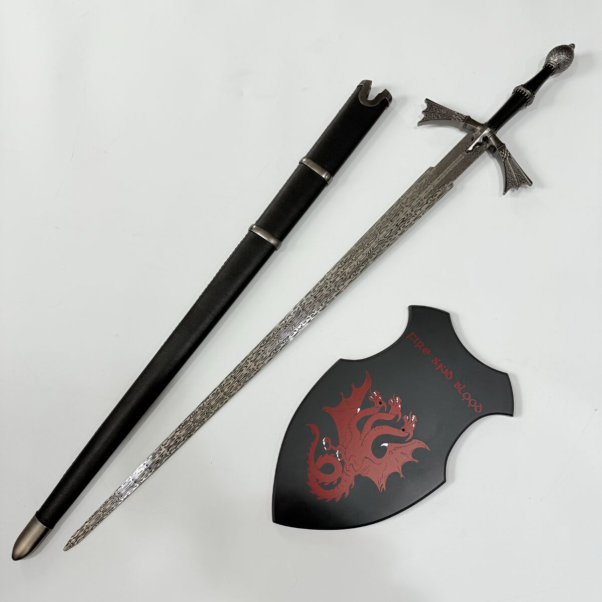 Decorative sword with sheath and shield featuring a dragon design on a white background