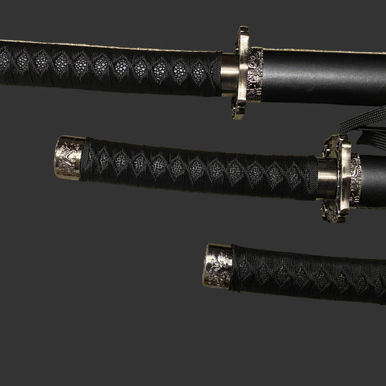 Three black samurai swords with gold accents on a gray background
