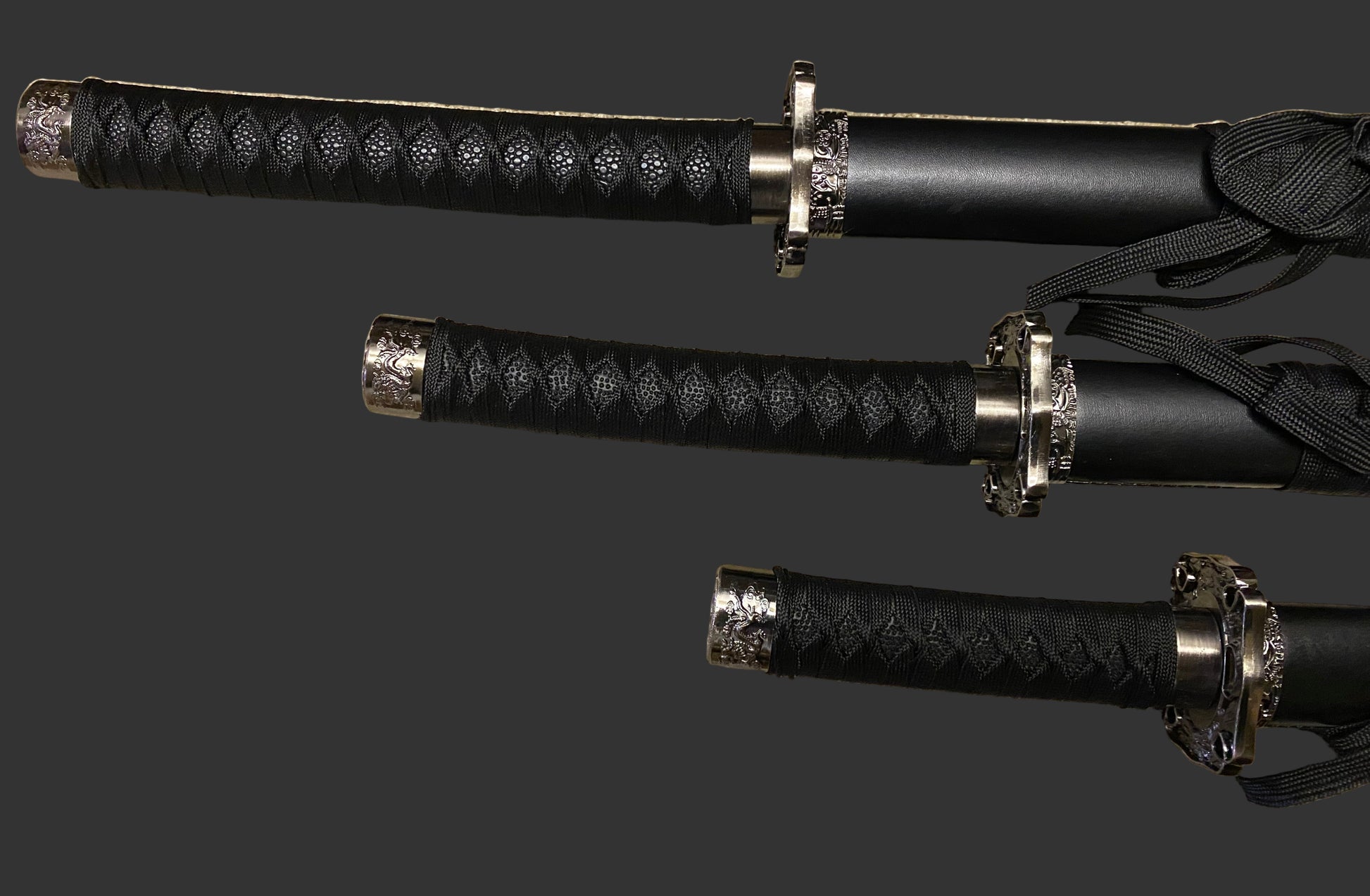 Three black samurai swords with gold accents on a gray background