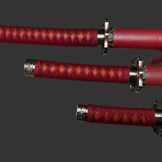 Three red swords with silver hilts on a gray background
