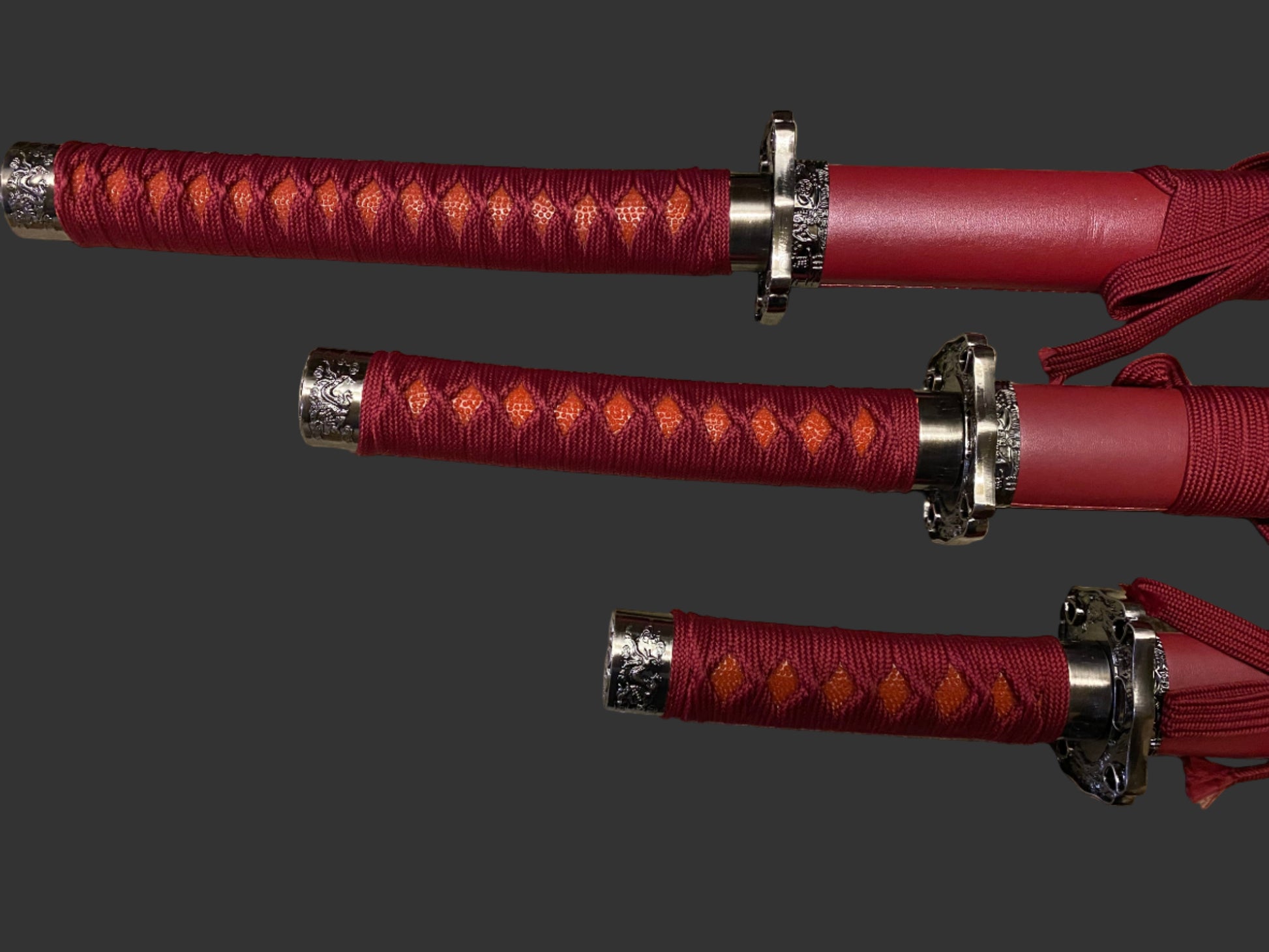 Three red swords with silver hilts on a gray background