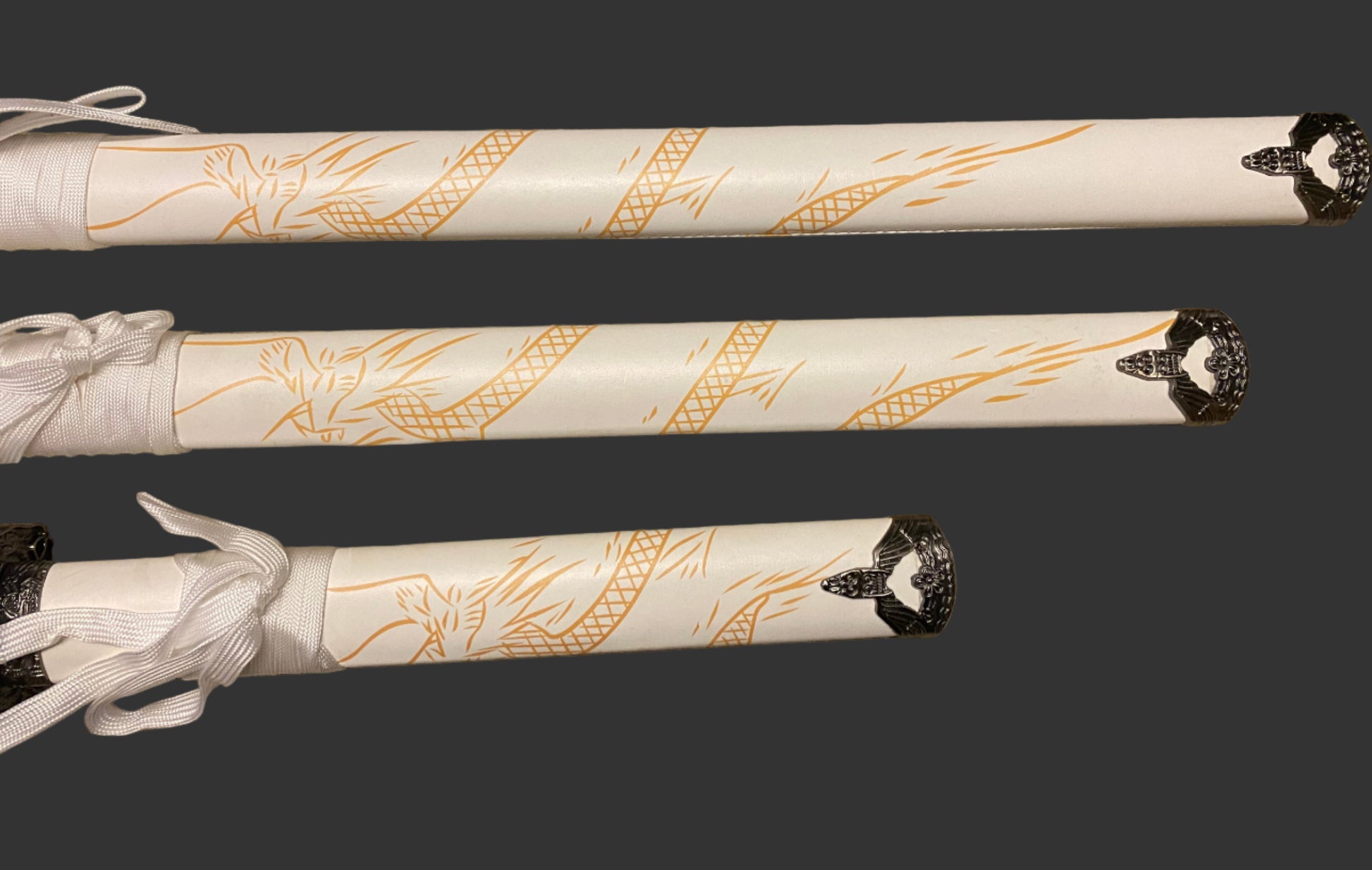 Three decorative sword sheaths with intricate gold patterns on a dark background
