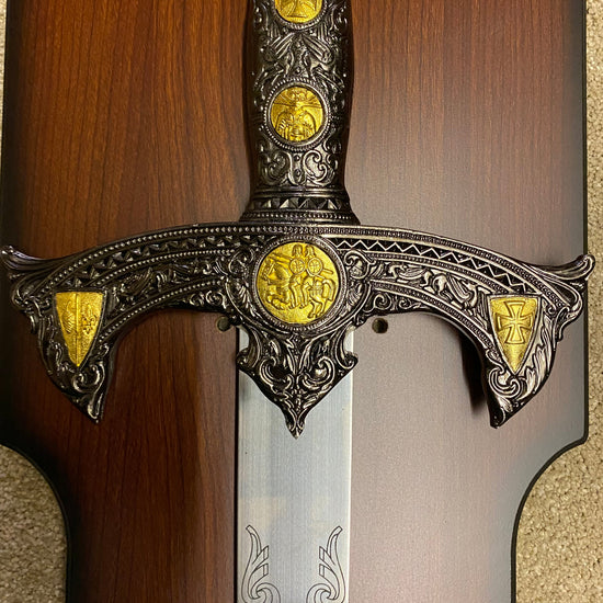 Decorative sword with ornate handle and gold embellishments on a wooden background