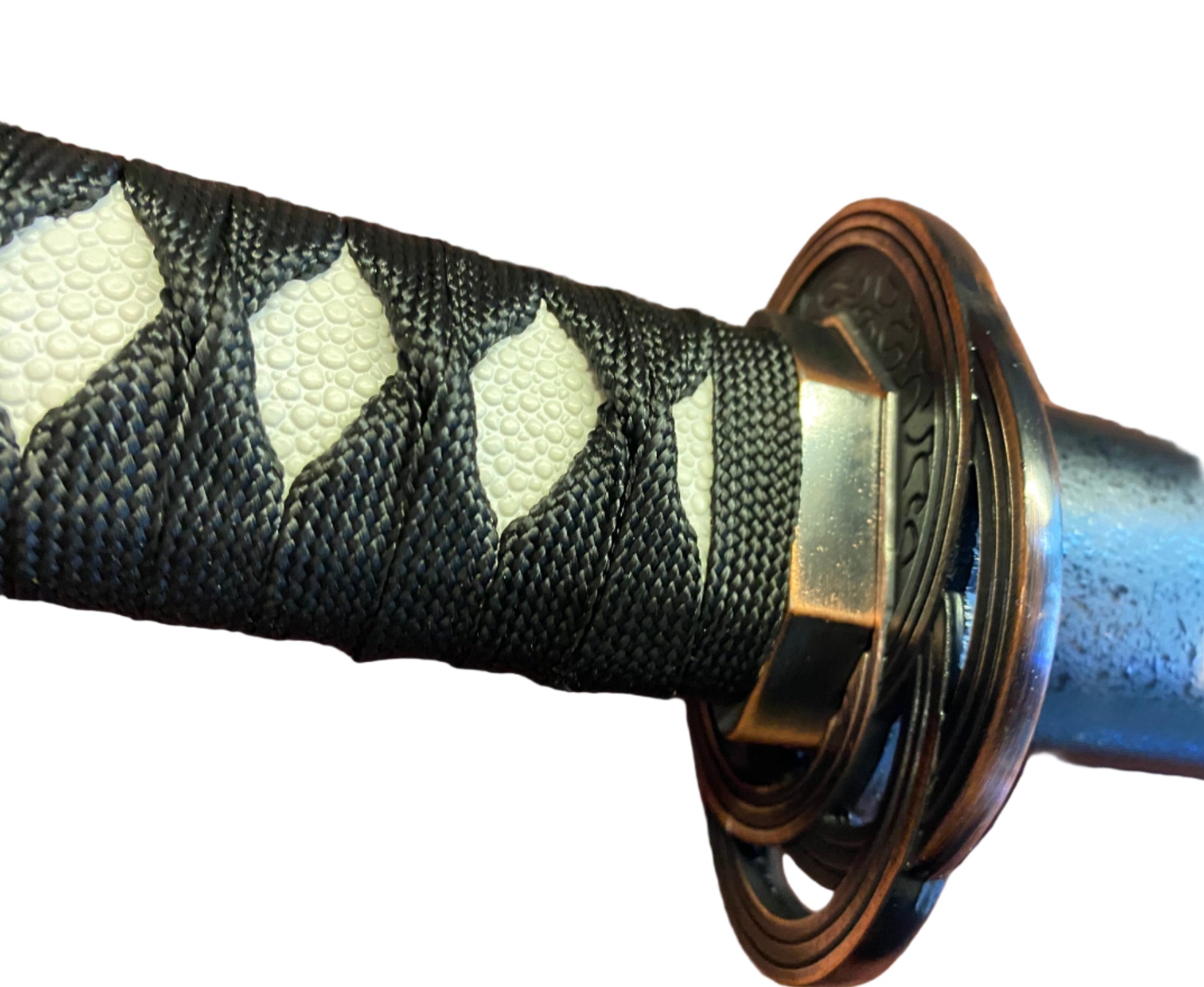 Close-up of a sword handle with black and white patterned grip and gold accents on a white background