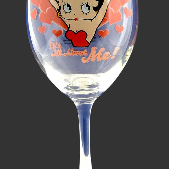 A clear wine glass featuring a Betty Boop illustration with red hearts and the text 'Be Mine' on a blue gradient background.