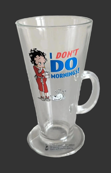 A clear glass mug with a handle and base, featuring a cartoon Betty Boop illustration and the text 'I DON'T DO MORNINGS!' in blue and red on a white studio background.
