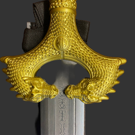 Decorative gold hilt of a sword on a dark background