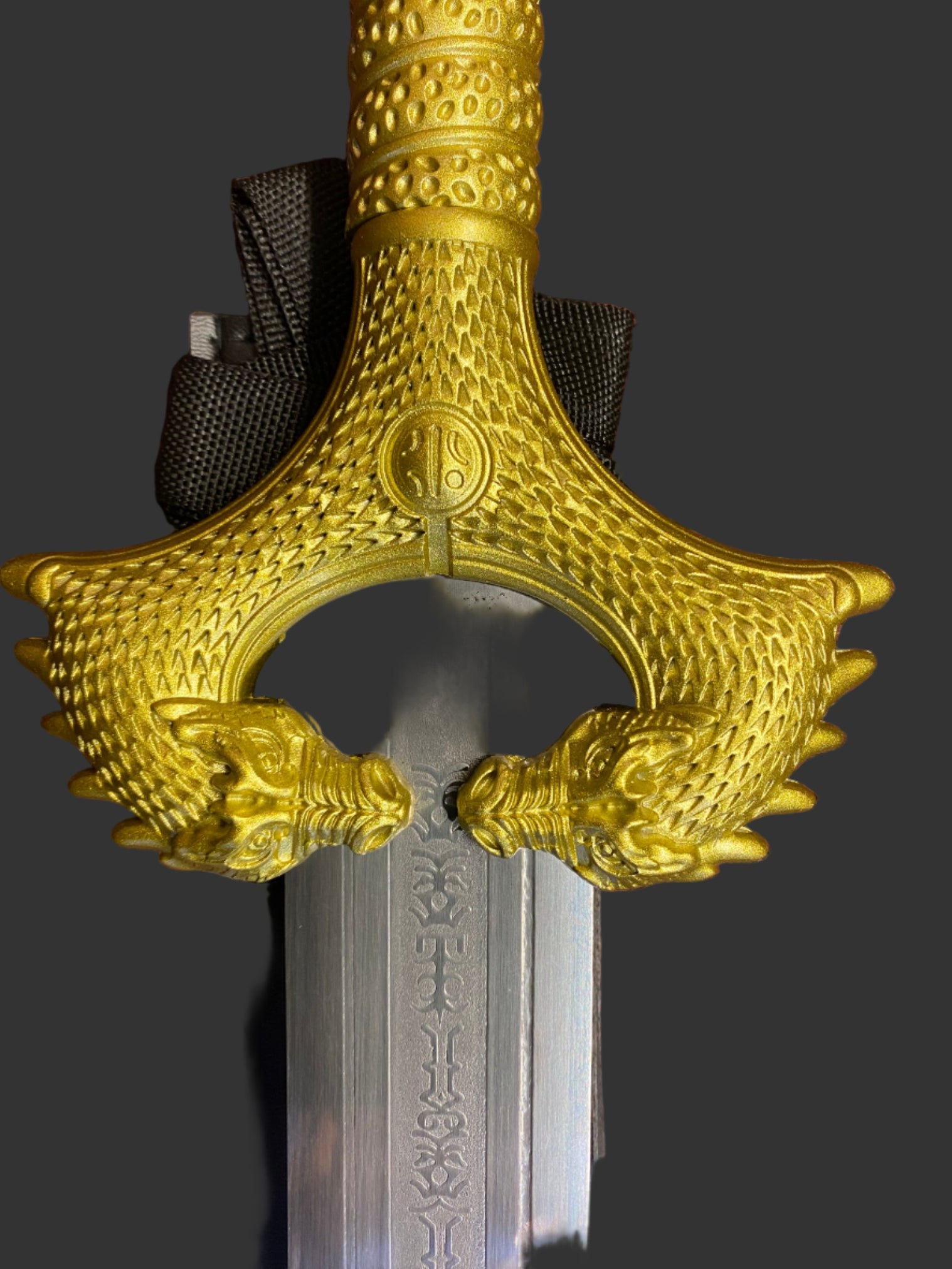 Decorative gold hilt of a sword on a dark background