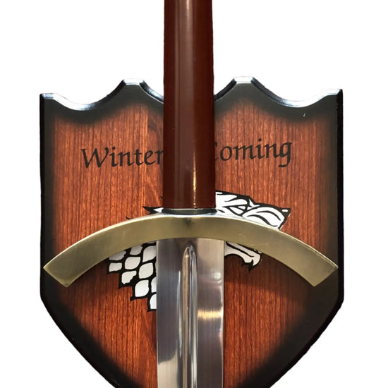 Sword with wooden sheath featuring 'Winter is Coming' text and a white wolf emblem on a red background.