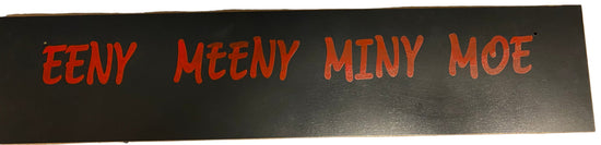 Strip of black material with red text 'EENY MEENY MINY MOE' on a white background