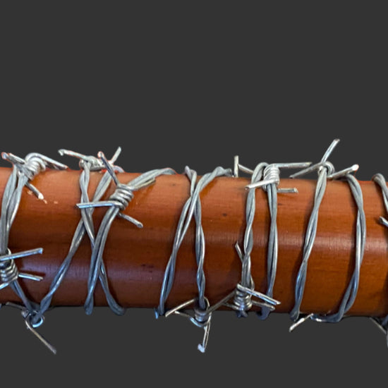 Wooden bat with barbed wire wrapped around it on a black background