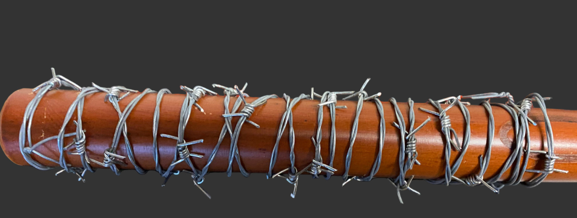 Wooden bat with barbed wire wrapped around it on a black background