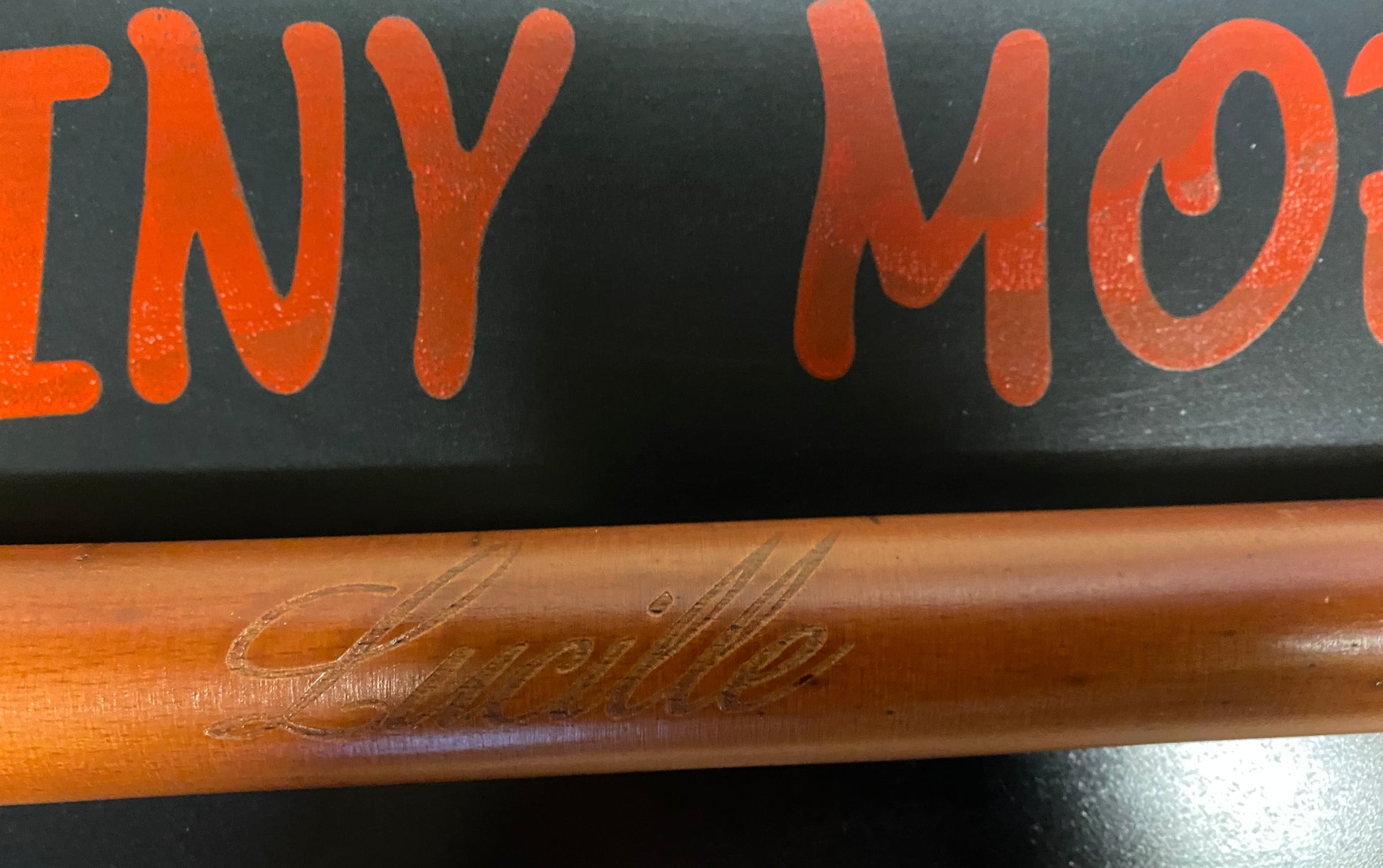 Wooden baseball bat with 'Lucchese' branding on a black background with orange text.