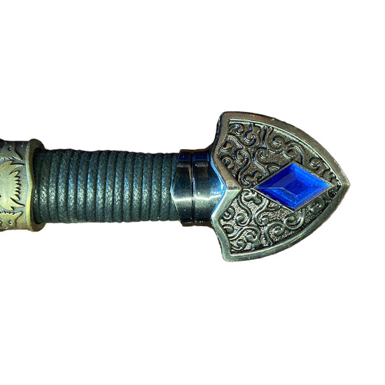 Decorative spear head with intricate designs and a blue gemstone on a white background
