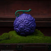 Purple textured object with a green handle on a grassy surface