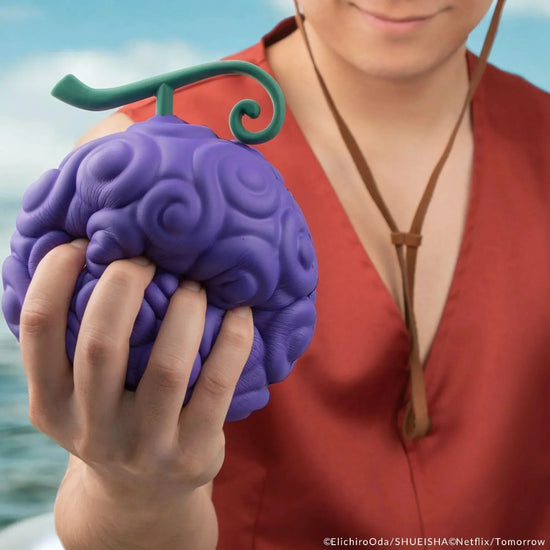 Person holding a purple brain-shaped object with a green stem against a blurred natural background