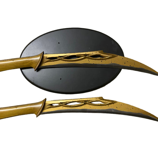 Two gold fantasy swords on a textured surface with a black circular object.