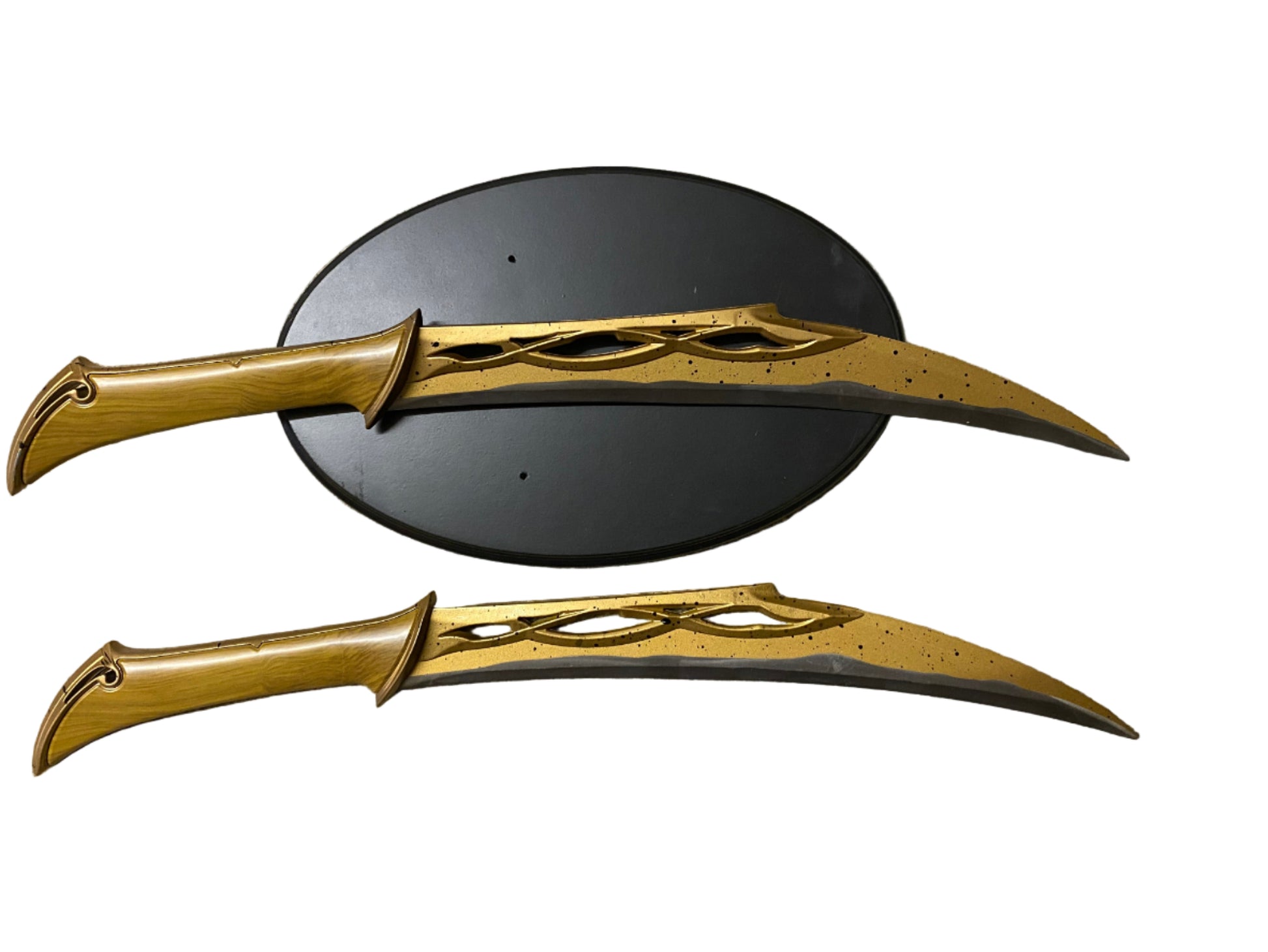 Two gold fantasy swords on a textured surface with a black circular object.