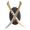 Two replica swords with bronze-colored handles and stainless steel blades, crossed in an X-shape on a black circular plaque, with the handles resting on top of the plaque.