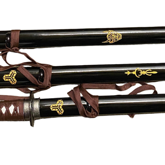 Three black samurai swords with brown sheaths on a white background