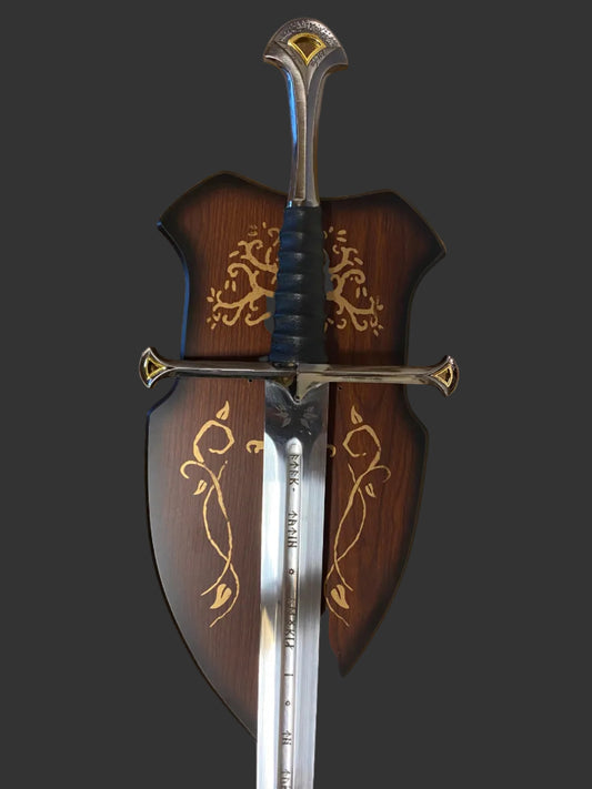 A decorative medieval-style sword with a polished silver blade, black wrapped hilt, and ornate gold detailing, shown alongside a matching dark brown wooden scabbard decorated with gold floral patterns.