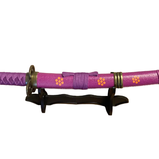 Purple  sword with decorative elements on a stand against a plain background