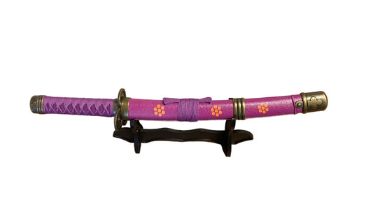 Purple  sword with decorative elements on a stand against a plain background