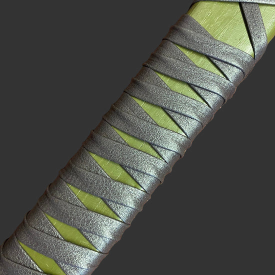 Close-up of a sword handle with green and gray pattern on a textured surface