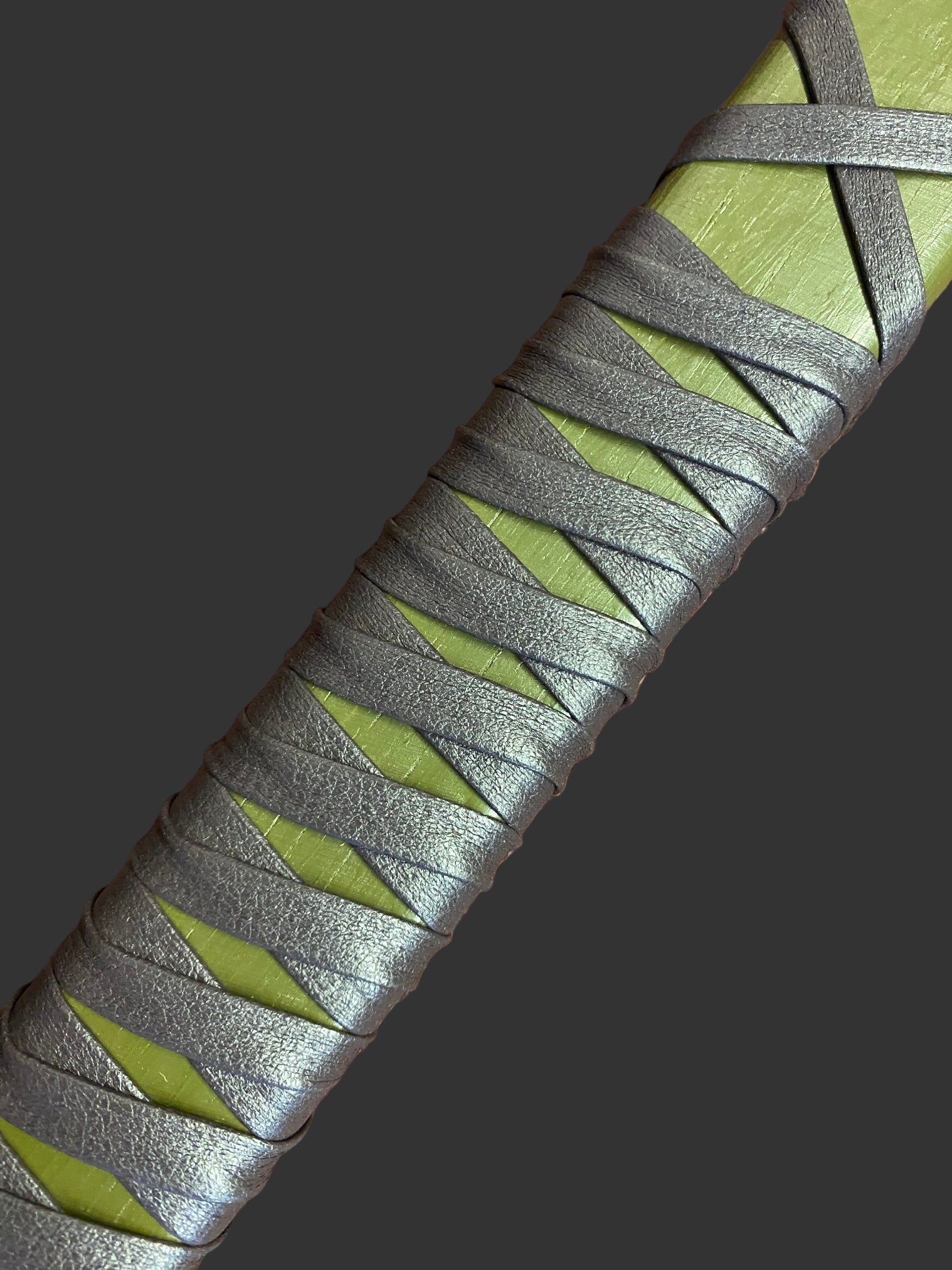 Close-up of a sword handle with green and gray pattern on a textured surface