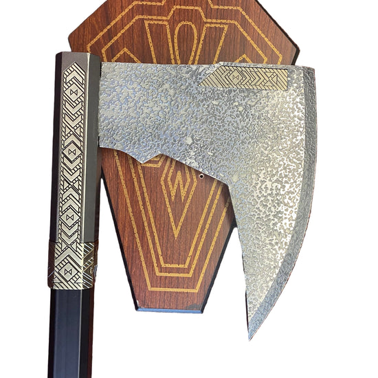 Decorative axe with wooden handle and metallic head on a textured surface