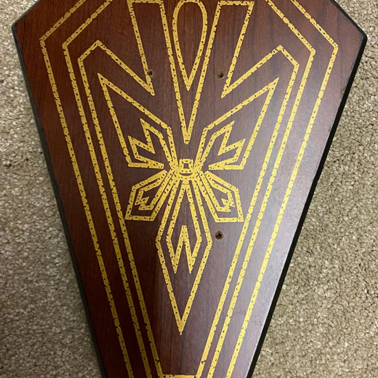 Decorative wooden panel with gold intricate design on a textured surface