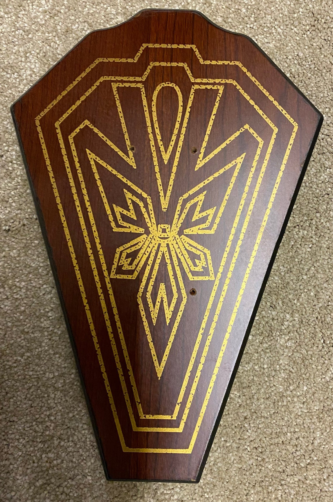 Decorative wooden panel with gold intricate design on a textured surface