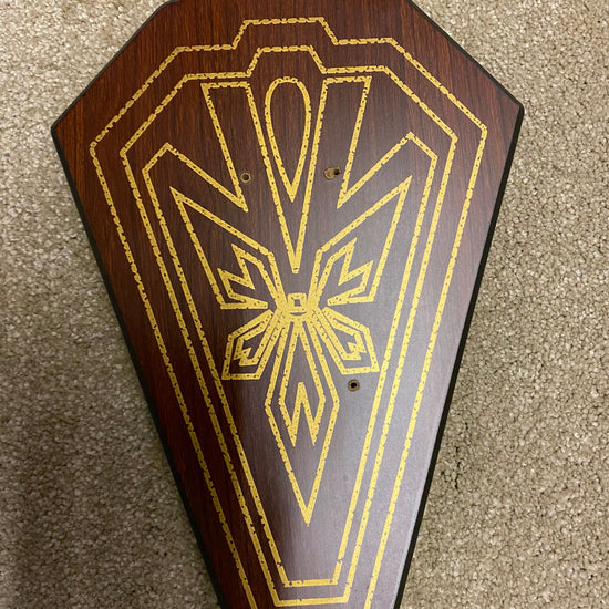 Wooden plaque with gold geometric design on a textured surface