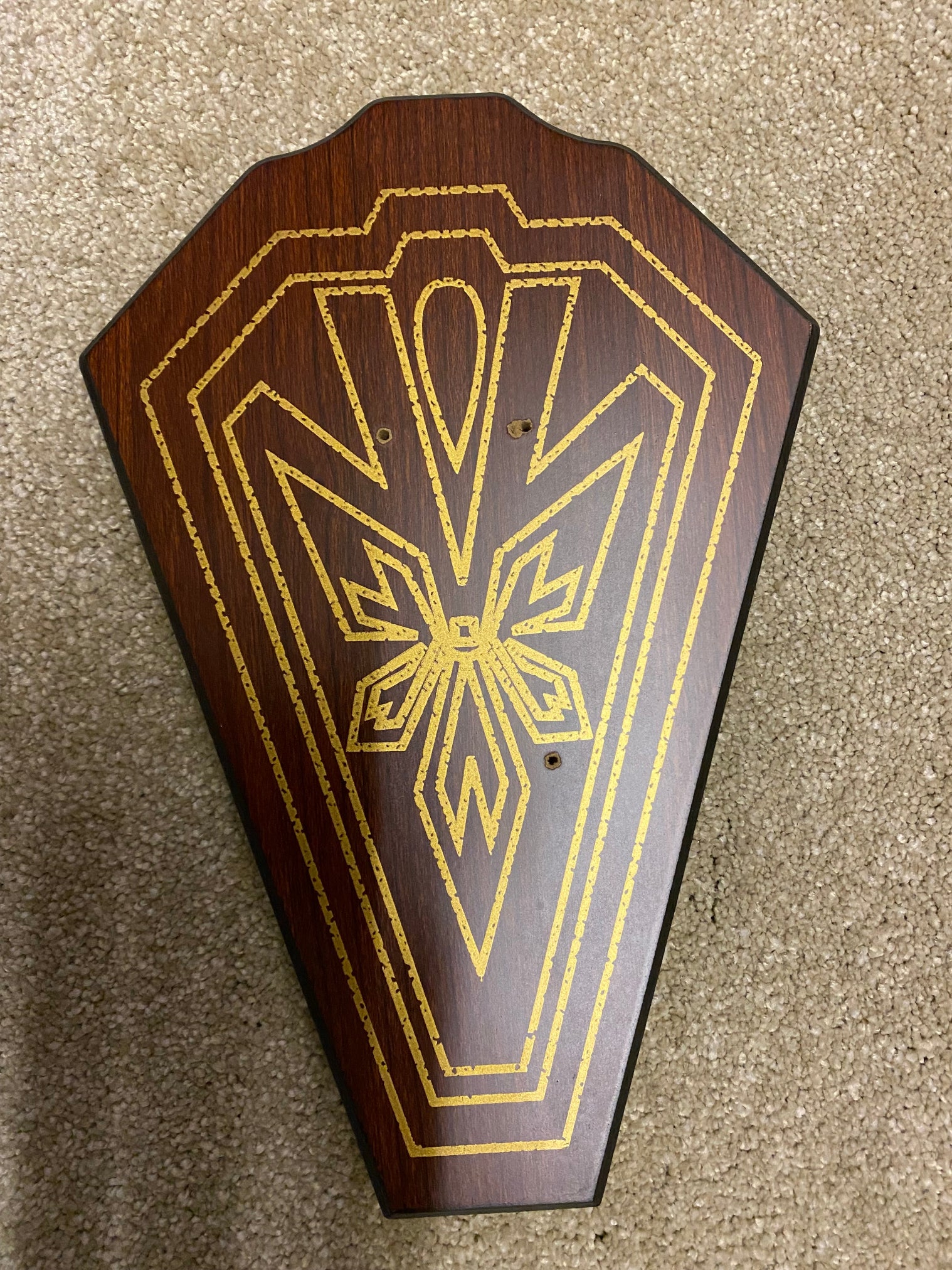 Wooden plaque with gold geometric design on a textured surface