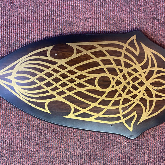 Decorative wooden plaque with gold intricate design on a purple textured background