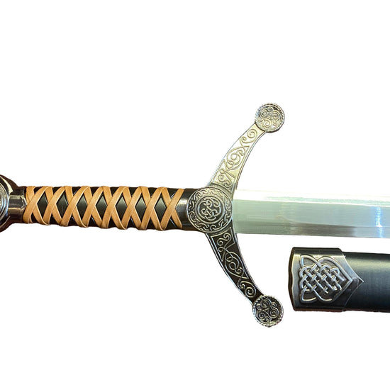 Decorative sword with ornate handle on a textured brown surface