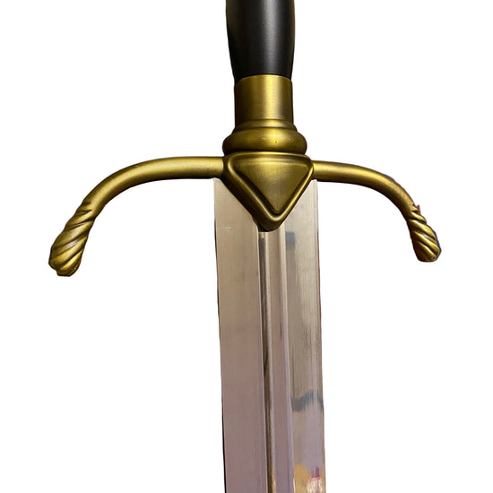 Decorative sword with gold and black handle on a black surface with red dragon design