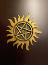 Gold sun-shaped symbol with a pentagram in the center on a dark background