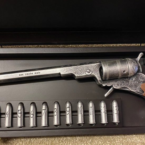 Decorative revolver with wooden grip and metal components in a display case.