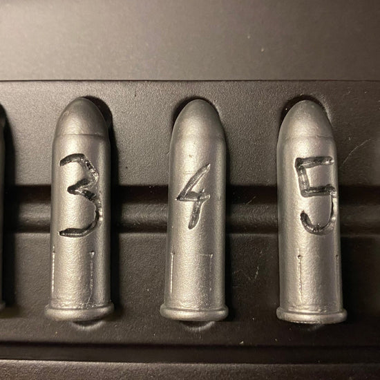Set of six metallic bullets with engraved numbers on a dark background