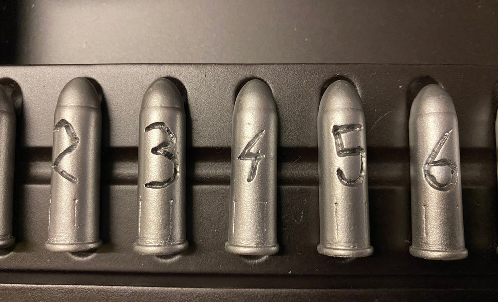 Set of six metallic bullets with engraved numbers on a dark background