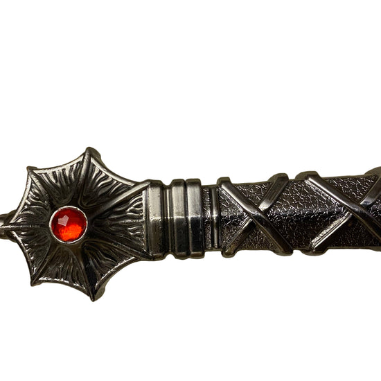 Decorative object with star design and red gemstone on a textured surface