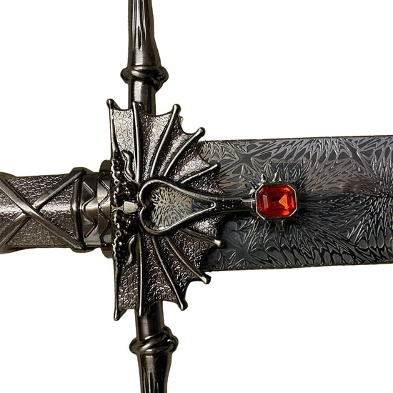 Decorative dagger with intricate design and red gemstone on a white background