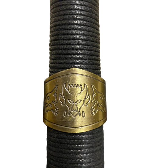 Black rope handle with a gold emblem on a textured surface