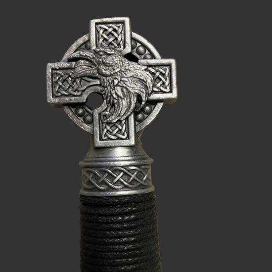 Decorative object with Celtic cross design featuring a bird, on a dark background.